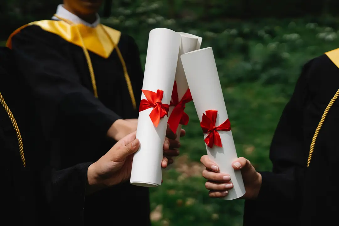 Three students holding their degree diplomas at graduation.