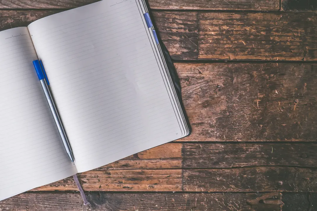 Open notebook and pen on a wooden desk