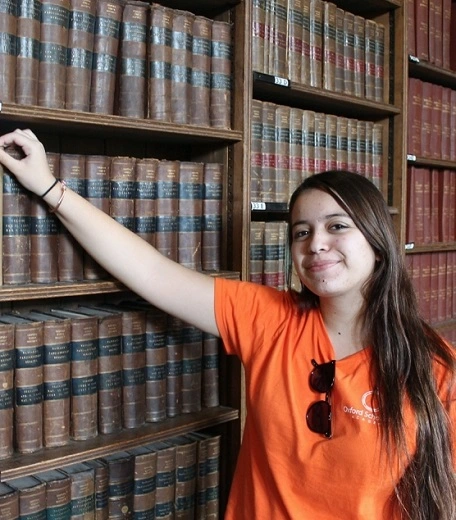 Person in Oxford Scholastica Academy tshirt posing in a library